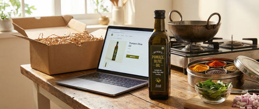 A bottle of authentic pomace olive oil on a kitchen counter next to a laptop displaying an e-commerce site to buy pomace olive oil in India.