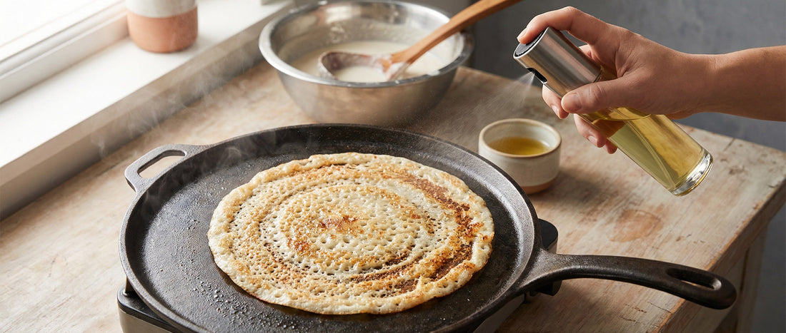 Crispy dosa cooking on a hot tawa with light sesame oil spray around the edges in an Indian home kitchen