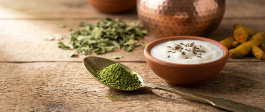 Pea-sized amount of moringa powder on a spoon next to curd, illustrating safe Indian dosage guidelines