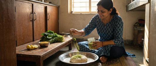 An Indian woman sprinkling iron-rich moringa powder into wheat flour dough to enrich a daily vegetarian meal and prevent anemia.